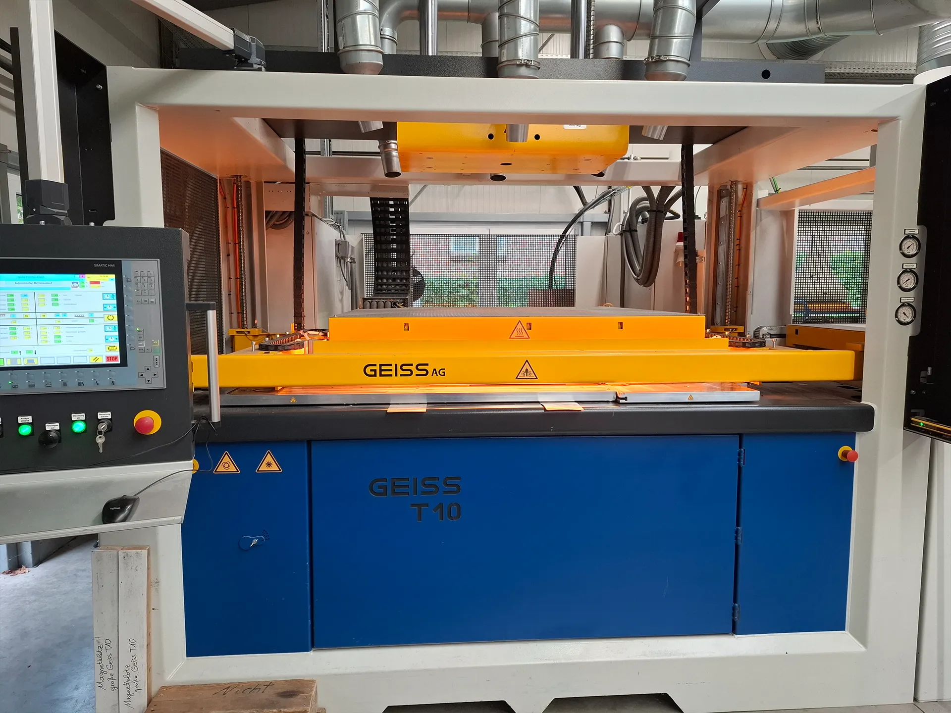 Industrielle GEISS T10 Presse mit gelber Heizplatte, Steuerpanel links und blauem Unterschrank